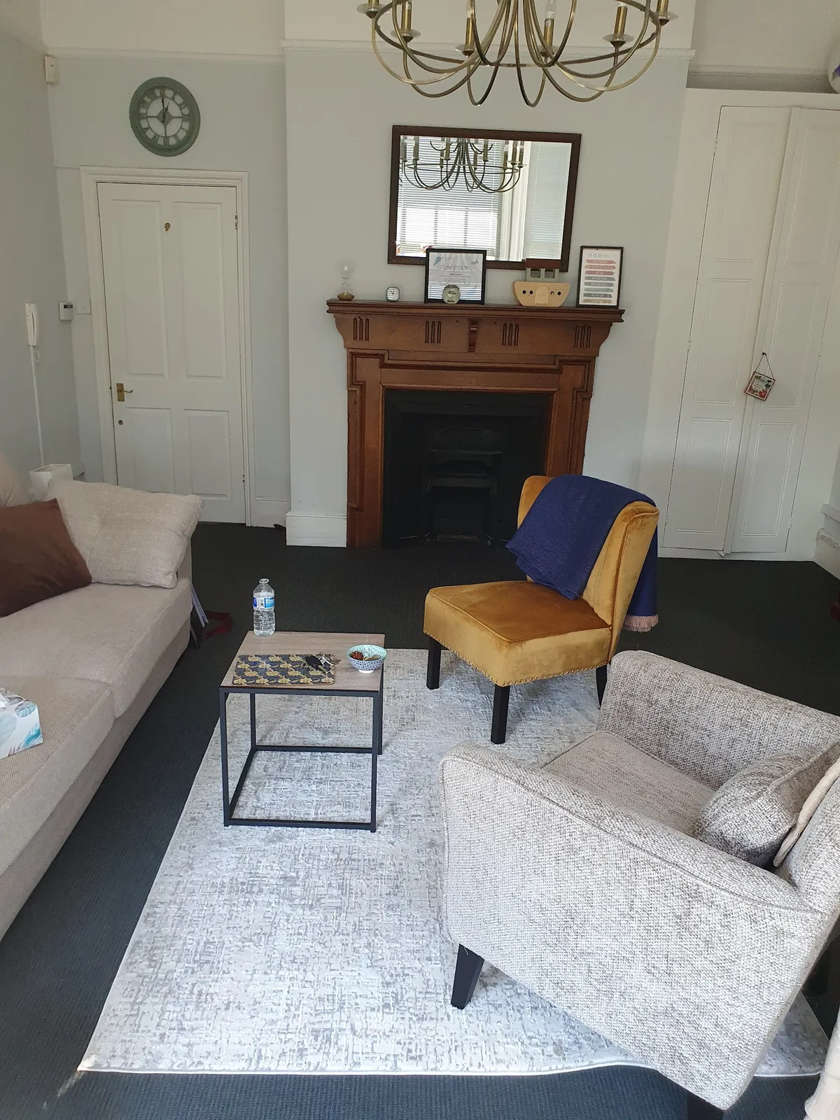 A mustard-yellow armchair beside the fireplace in the Marlow consulting room.